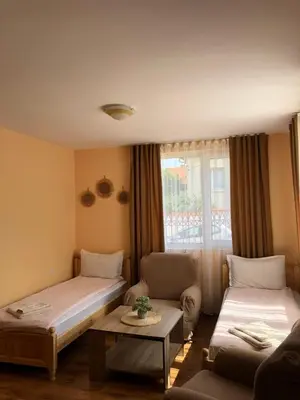 a room with two beds and a couch and a table at Holiday guest house KEMO in Sapareva Banya