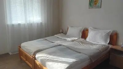 a bed with white sheets and pillows and a window at Holiday guest house KEMO in Sapareva Banya