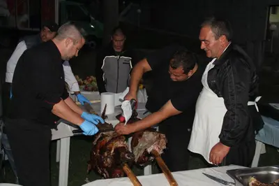a group of men preparing a roast turkey on a table at Borika Hotel in Chepelare