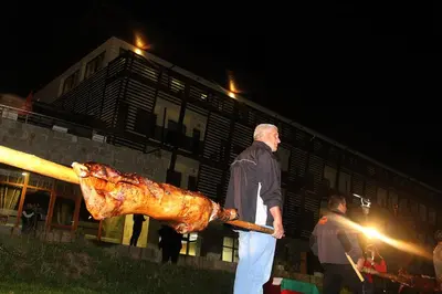 a man holding a roasted chicken on a bat at Borika Hotel in Chepelare