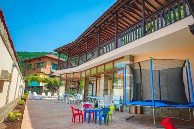 a patio with colorful chairs and tables in front of a building at Стаи за гост Хит Хаус и СПА in Bratsigovo
