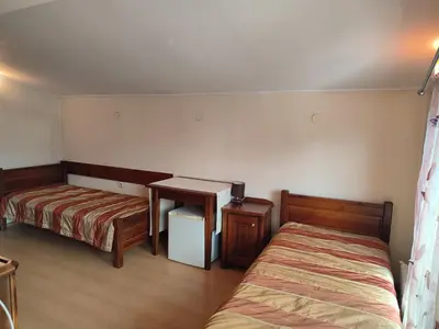a bedroom with two beds and a desk and a table at Къща за гости M-Stone in Bansko