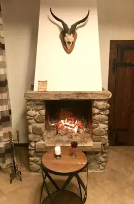 a living room with a stone fireplace with a table at Relax in Dobrinishte