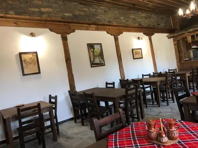 a dining room with wooden tables and chairs at Пачаловата къща in Kovachevitsa