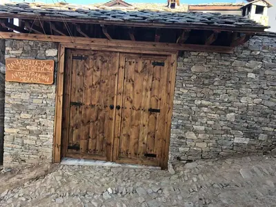 a wooden door on the side of a stone building at Пачаловата къща in Kovachevitsa