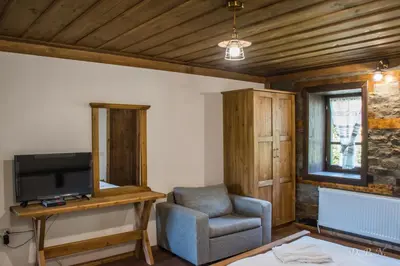 a living room with a chair and a television at Пачаловата къща in Kovachevitsa