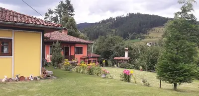 a house with a yard with flowers in front of it at Mechta Guest House in Koprivshtitsa