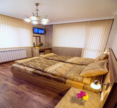 a bedroom with a large bed and a television at Trite Bora Guest House in Narechenski Bani
