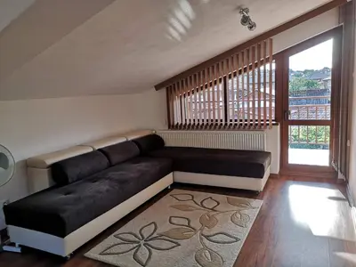 a living room with a black couch and a large window at стаи за гости Диневи in Kalofer