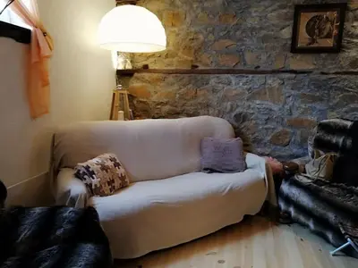 a living room with a couch and a stone wall at EskiZ - Our stone home in Chepelare