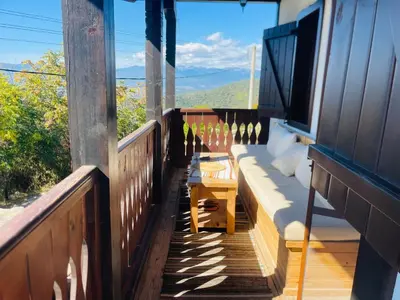 a balcony with a table and a view of the mountains at Къща за гости Родопски изгрев in Leshten