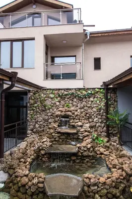 a house with a stone wall with a water fountain at Etobicoke -Стаи за гости in Etropole