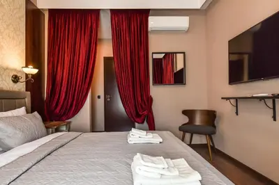 a bedroom with red curtains and a bed with towels on it at Palace of Culture 2-Bedroom Retreat on Skobelev blvd in Sofia