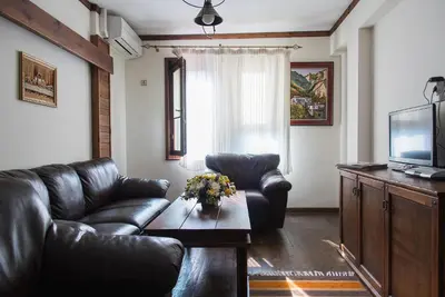 a living room with a leather couch and a television at Zlaten Rozhen Family Hotel- Monument of Cultural Significance in Rozhen