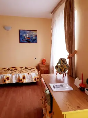 a bedroom with a bed and a desk and a window at Hadjibulevata Guest House in Kovachevtsi
