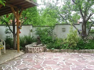 a backyard with a stone patio with a stone table at Hadjibulevata Guest House in Kovachevtsi