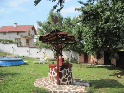 a bird statue in a yard with a umbrella at Hadjibulevata Guest House in Kovachevtsi