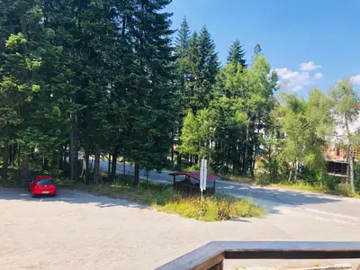 a red car parked in a parking lot with trees at Studio Villa Park Premium Gold in Borovets