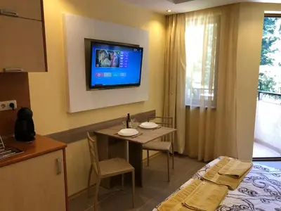 a room with a table and a tv on the wall at Studio Villa Park Premium Gold in Borovets