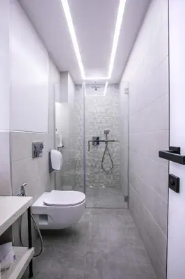 a white bathroom with a toilet and a shower at South Place Apartments in Sandanski