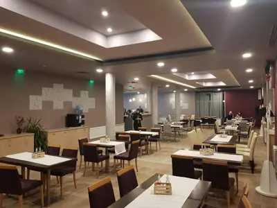 a restaurant with tables and chairs and people in the background at Апартаментен туристически комплекс Аква Терми in Krasnovo