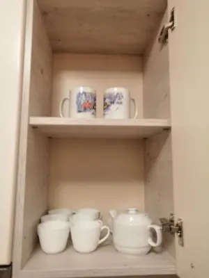 a cupboard filled with white cups and saucers at Apartments in Borovets Gardens in Borovets