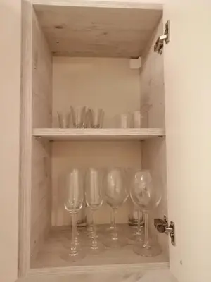 a row of wine glasses in a cupboard at Apartments in Borovets Gardens in Borovets