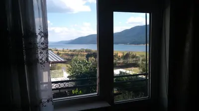 a window with a view of a lake and mountains at Айрови in Sarnitsa
