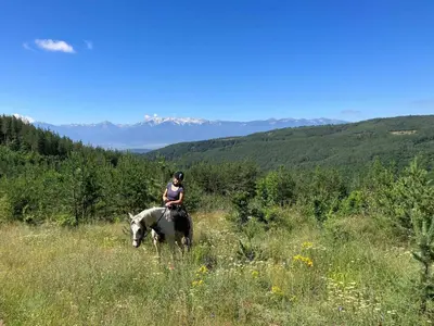 a woman riding a horse in a field at Rusaliite Adventure House in Bachevo