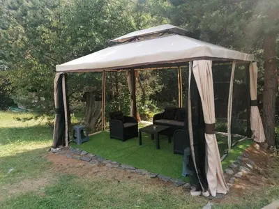 a gazebo with chairs and a table in the grass at Rusaliite Adventure House in Bachevo