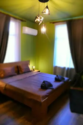 a bedroom with a bed with green walls and windows at Art Apartment 36 in Plovdiv