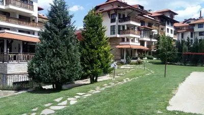 a yard in front of a building with trees at Apartman u kompleksu Royal Towers in Bansko