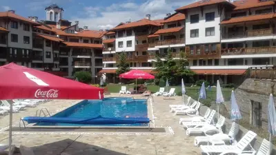 a swimming pool with chairs and umbrellas in a resort at Apartman u kompleksu Royal Towers in Bansko