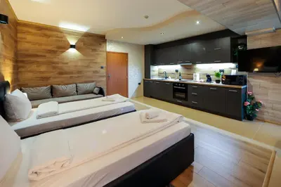 two beds in a room with a kitchen at Family Hotel Gotse Delchev in Gotse Delchev