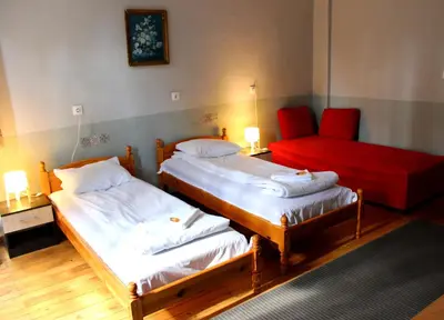 two beds in a room with a red chair at Santa Sofia in Sofia