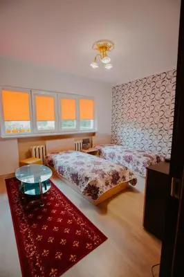 a bedroom with two beds and a table and a rug at Dimitrovi Rooms in Sofia