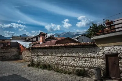 an old stone building with mountains in the background at NEXT TO GONDOLA. Cosy & Elegant 2 Bedroom apartment in Neon Complex in Bansko