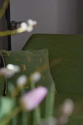 a green pillow sitting on a couch with flowers at The Embassy Suites in Sofia