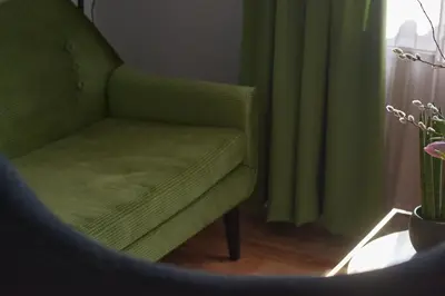 a green chair in a room with a window at The Embassy Suites in Sofia