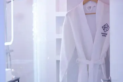 a white robe hanging on a door in a bathroom at The Embassy Suites in Sofia