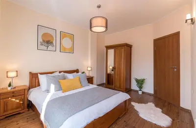 a bedroom with a large bed and a wooden cabinet at Charming Ski Apartments Near Gondola & Bar Street, Cedar Lodge 1 Complex in Bansko