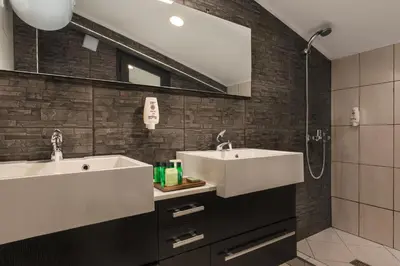 a bathroom with two sinks and a shower at Hotel Villa Magus in Kladnitsa
