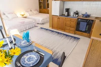 a kitchen with a table and a room with two beds at Аpartment Gem in Centre of Sandanski in Sandanski