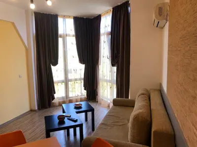 a living room with a couch and large windows at Fantasy Apartment 15 комплекс Фантазия, Хисаря in Hisarya