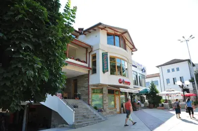 a building on a street with people walking in front of it at Plaza Family Hotel in Smolyan