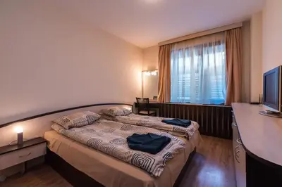 a bedroom with a bed and a desk and a television at Charming, Fully-furnished, 2-bedroom apartment by Flat Mаnager in Bansko