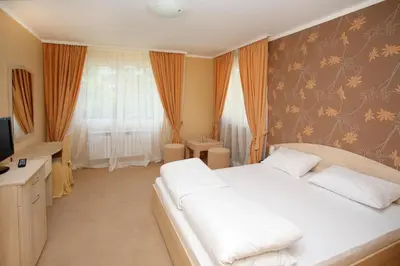 a bedroom with a white bed and a television at Family Hotel Diana in Sofia