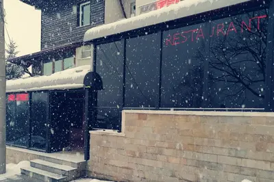 a train station in the snow in front of a building at Discret Hotel & Restaurant in Vladaya