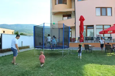a group of people standing in a yard with a playground at Семеен Хотел Дани in Asenovgrad