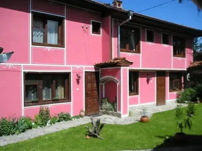 a pink building with a yard in front of it at Nenchova Guest House in Koprivshtitsa
